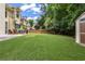Landscaped backyard featuring a large grassy area, brick patio, playground and shed at 350 Medridge Dr, Johns Creek, GA 30022