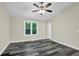 Bright bedroom features gray wood flooring, neutral walls, white trim, a ceiling fan, and a backyard view from the window at 3571 Kennesaw Station Nw Dr, Kennesaw, GA 30144