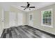 Bright bedroom features gray wood flooring, neutral walls, white trim, a ceiling fan, and a backyard view from the window at 3571 Kennesaw Station Nw Dr, Kennesaw, GA 30144