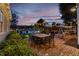 Inviting backyard brick patio features dining, lounge seating and a swing beneath string lights at dusk near the swimming pool at 525 E Main St, Buford, GA 30518