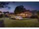 A home's backyard at dusk featuring an in-ground pool, patio, lounge seating, well-manicured lawn and landscape lighting at 525 E Main St, Buford, GA 30518