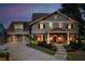 Charming two-story home with manicured landscaping, exterior lighting, and three car garage at dusk at 525 E Main St, Buford, GA 30518