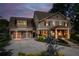 Attractive two-story home with professional landscaping, exterior lighting, and a three car garage at dusk at 525 E Main St, Buford, GA 30518