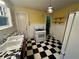 Compact kitchen featuring black and white checkered flooring, basic appliances, and bright yellow walls at 3366 College St, College Park, GA 30337