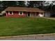 Charming single-story home with a vibrant red brick facade, complemented by a large, well-manicured front yard and mature trees at 1830 Brandy Se Ln, Conyers, GA 30013