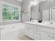 Well-lit bathroom with double sinks, a large tub, and a window providing natural light at 6034 Farmwood Se Way, Mableton, GA 30126