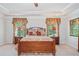 Bedroom with a trey ceiling, large windows with decorative curtains and lamps on both bedside tables at 3230 Sundew Nw Dr, Acworth, GA 30101