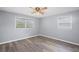Bedroom featuring two windows, neutral gray walls, wood-look floors, ceiling fan and white trim at 6997 Vesta Brook Dr, Morrow, GA 30260
