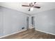 Cozy living room with gray paneled walls, ceiling fan, and wood-look floors leads to the stairway at 6997 Vesta Brook Dr, Morrow, GA 30260