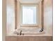Elegant soaking tub situated beneath a window with decorative trim and tiling at 1584 Water Springs Way, Dacula, GA 30019