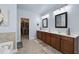 Bathroom boasting double vanity, wood cabinets, decorative mirrors, and access to walk-in closet at 4690 Hopewell Manor Dr, Cumming, GA 30028