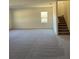 Spacious carpeted living room with a staircase and natural light at 7785 Sudbury Cir, Covington, GA 30014