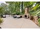Large stone patio with outdoor fireplace, comfortable seating, and wrought-iron fence at 10000 Groomsbridge Rd, Johns Creek, GA 30022