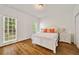 Cozy bedroom featuring hardwood floors, two windows, a white bed, and side tables with lamps at 10000 Groomsbridge Rd, Johns Creek, GA 30022