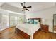 Primary bedroom with large bed, hardwood floors, tray ceiling, and natural light from shuttered windows at 10000 Groomsbridge Rd, Johns Creek, GA 30022