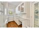 Butler's pantry features white cabinetry, display cabinets, granite counters, tile backsplash, and hardwood flooring at 10000 Groomsbridge Rd, Johns Creek, GA 30022