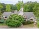 Exterior of a gabled home with a stone accent, tidy landscaping, and a small lake with fountain in the backyard at 10000 Groomsbridge Rd, Johns Creek, GA 30022