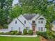 Charming two-story home with a red front door and lush landscaping in a serene, wooded setting at 10000 Groomsbridge Rd, Johns Creek, GA 30022
