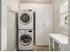 Efficient laundry area with stacked washer and dryer, white storage cabinets, and a folding counter at 10000 Groomsbridge Rd, Johns Creek, GA 30022