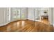 Sunlit living room featuring shiny hardwood floors and three bay windows with wooden shutters at 10000 Groomsbridge Rd, Johns Creek, GA 30022