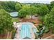 Aerial view of the community pool with a waterslide, pool, seating, and surrounding mature trees at 10000 Groomsbridge Rd, Johns Creek, GA 30022