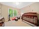 Serene Bedroom with a wooden crib, soft lighting, a comfortable rocking chair, and a view of a wooded area at 790 Sienna Dr, Cumming, GA 30040