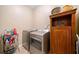 A laundry room with a wooden cabinet, a metal shelf, and stainless steel washer and dryer at 790 Sienna Dr, Cumming, GA 30040