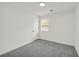 Bright, empty bedroom with grey carpets, a door, and a single window at 1645 Cobbs Creek Ln, Decatur, GA 30032