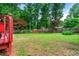Spacious backyard featuring a lush lawn, vibrant trees, and a charming red storage shed at 273 Hardwood Ln, Lawrenceville, GA 30044