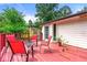 View of the outdoor deck featuring charming red deck, four chairs, and a lush green backdrop at 273 Hardwood Ln, Lawrenceville, GA 30044