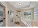Bathroom showcasing a chandelier, tiled floor, soaking tub under a window, a sink, and the toilet in an adjacent room at 6009 Castleton Mnr, Cumming, GA 30041