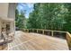 Relaxing outdoor deck featuring wood flooring, cable railings, seating, and wooded landscape views at 6009 Castleton Mnr, Cumming, GA 30041