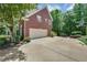 A well-maintained two-car garage with a large driveway and basketball hoop, nestled in a lush, wooded landscape at 6009 Castleton Mnr, Cumming, GA 30041