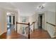 Hallway with hardwood floors, white railings, and access to multiple rooms and the staircase at 6009 Castleton Mnr, Cumming, GA 30041
