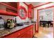 Stylish wet bar with red cabinets, granite countertops, and a decorative window at 4470 Crestwicke Pointe, Atlanta, GA 30319