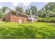 Large backyard showcasing a brick house, green lawn, and mature trees at 2118 Allaire Ne Ln, Atlanta, GA 30345