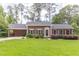 Charming one-story brick home featuring a manicured lawn, colorful flowers, and mature trees at 2118 Allaire Ne Ln, Atlanta, GA 30345
