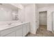 Bright bathroom featuring a double sink vanity, large mirror, and a door leading to the walk-in closet at 215 Amberjack Trail, Covington, GA 30016