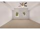 Large main bedroom with a tray ceiling, a ceiling fan, neutral carpeting, and large windows at 215 Amberjack Trail, Covington, GA 30016
