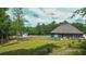 A wide expanse of a backyard with green grass and lush trees with a partially fenced in area at 1056 Riverstone Dr, Social Circle, GA 30025