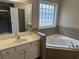 Bathroom featuring a soaking tub, tile surround, and dual vanity at 1266 Laurelwood Ct, Lawrenceville, GA 30045