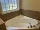 A close-up view of a corner soaking tub with tile surround and glass block window at 1266 Laurelwood Ct, Lawrenceville, GA 30045