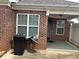 Red brick patio with awning, complemented by windows with blinds and a black garbage can at 1266 Laurelwood Ct, Lawrenceville, GA 30045