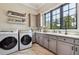 Bright laundry room featuring wood-look tile floors, grey cabinets, and a large window with a sink at , Buford, GA 30518