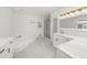 Bright bathroom with marble floors, soaking tub, modern vanities, a frameless shower door, and an updated vanity at 1887 Chedworth Ct, Stone Mountain, GA 30087