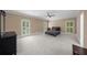 Spacious bedroom featuring neutral walls, plush carpet, ceiling fan, and natural light from the many surrounding windows at 1887 Chedworth Ct, Stone Mountain, GA 30087