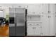 An open kitchen has stainless steel refrigerator and white cabinets with black hardware at 1887 Chedworth Ct, Stone Mountain, GA 30087