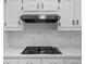 A gas cooktop sits in a modern kitchen with white cabinets and stainless steel vent at 1887 Chedworth Ct, Stone Mountain, GA 30087