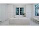 Bright bathroom featuring a luxurious soaking tub, white marble finishes, and built in shelving at 3382 Habersham Rd, Atlanta, GA 30305