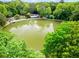 Aerial view of a neighborhood pond with trees surrounding, creating a relaxing atmosphere at 4108 Gray Birch Ln, Duluth, GA 30096